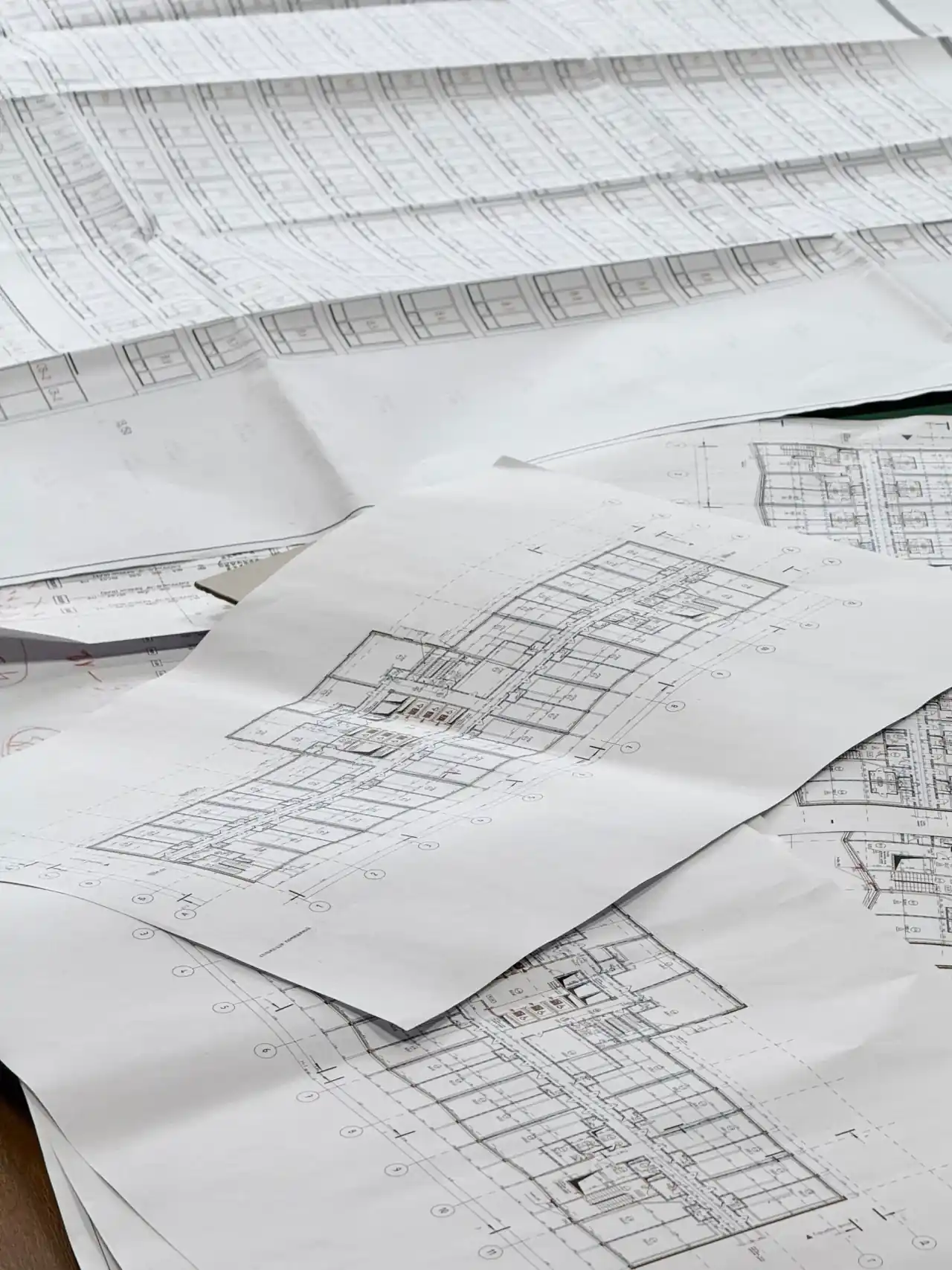 Detailed architectural and engineering plans arranged across a drafting table