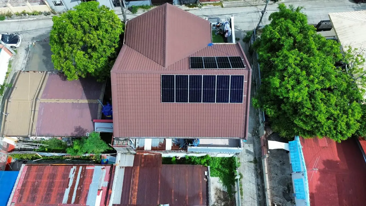 Top-down aerial view of ten solar panels across two planes of a brown roof
