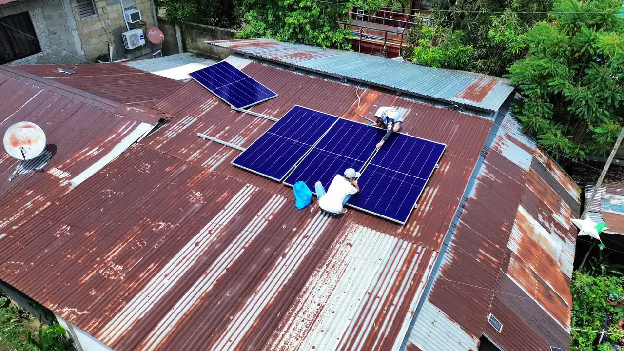 Aerial view of four solar panels installed on a weathered metal roof