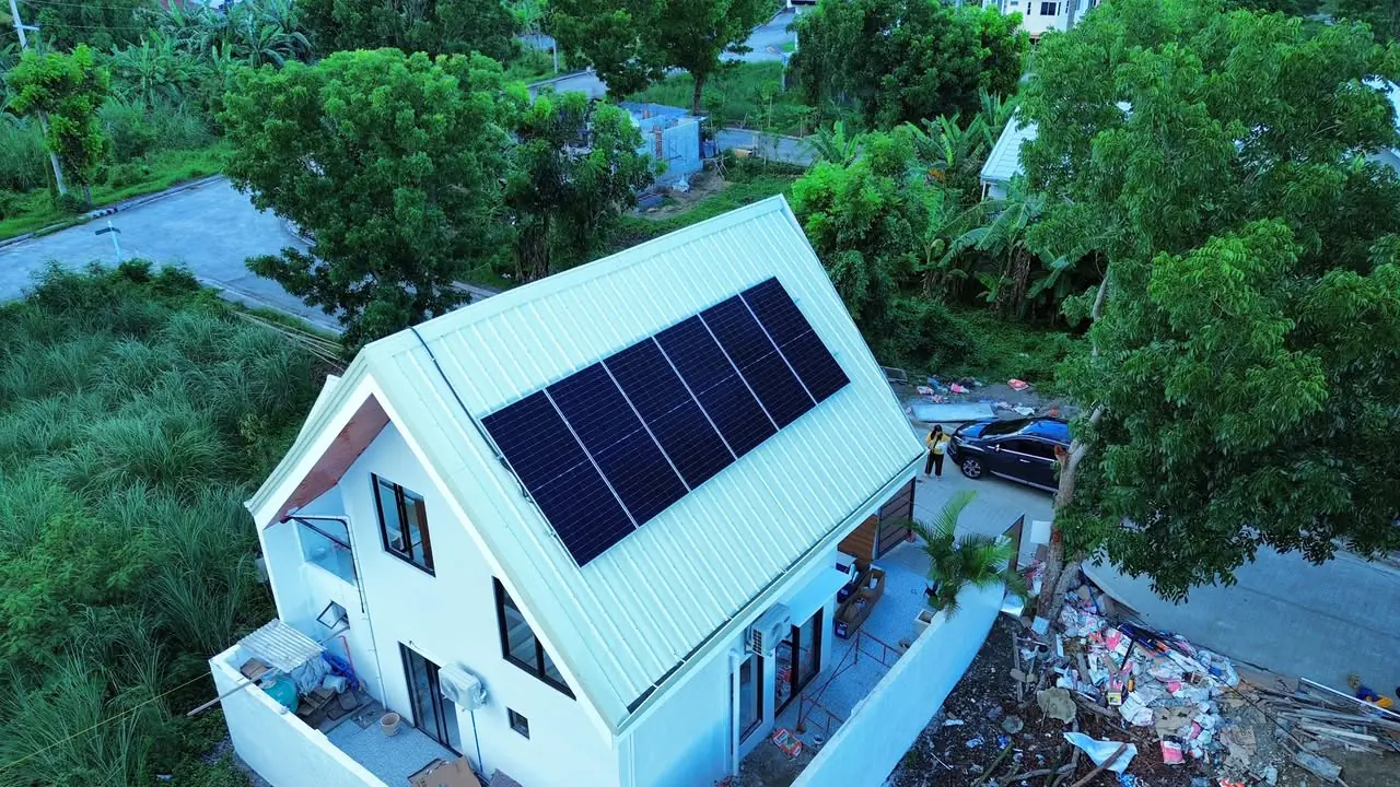 Aerial view of twelve solar panels on the pale roof of a two-story home