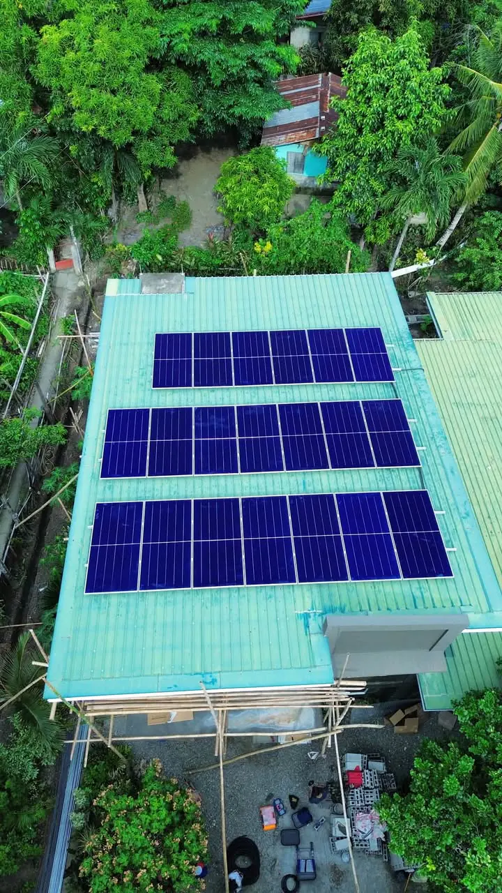 Aerial view of four solar panel rows installed on a green residential roof