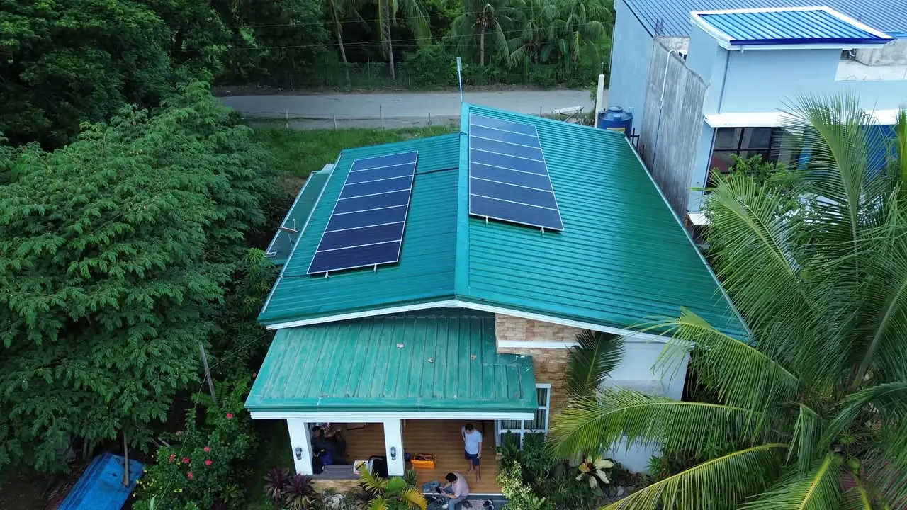 Angled aerial view of two solar panel banks on a green metal roof