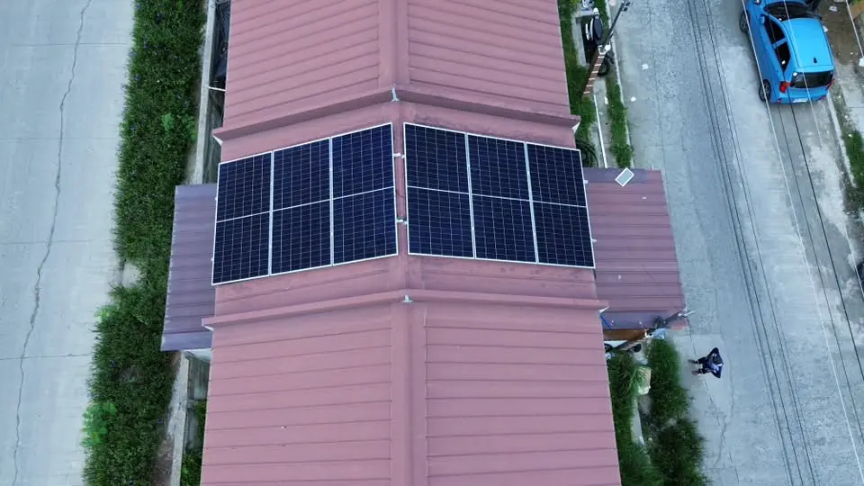 Aerial view of six solar panels arranged across both sides of a pink metal roof